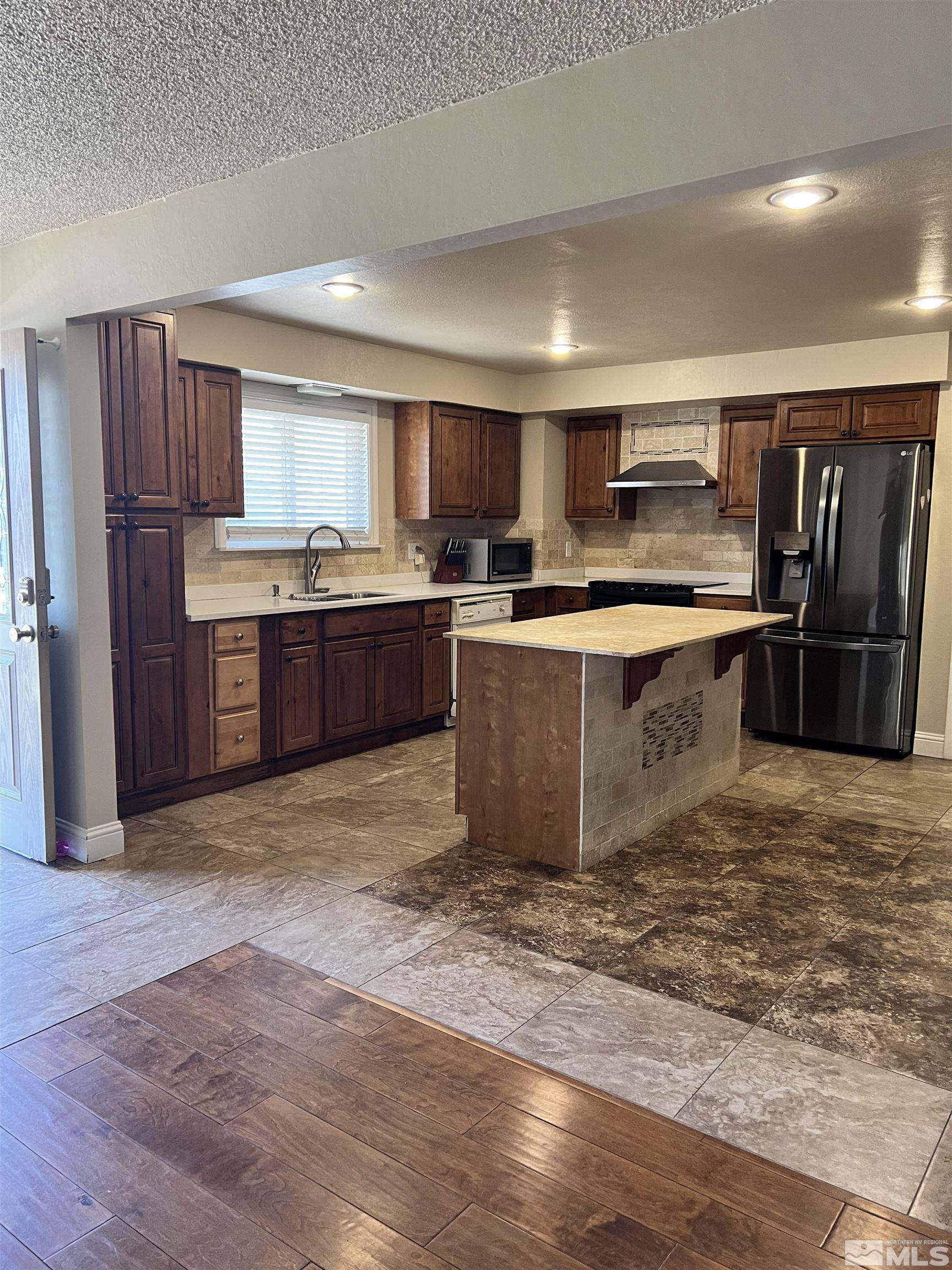 908 Lester Avenue Reno, NV 89502 - Photo 2 of 35 a kitchen with stainless steel appliances granite countertop a stove top oven a sink dishwasher a refrigerator and a dining table with wooden floor