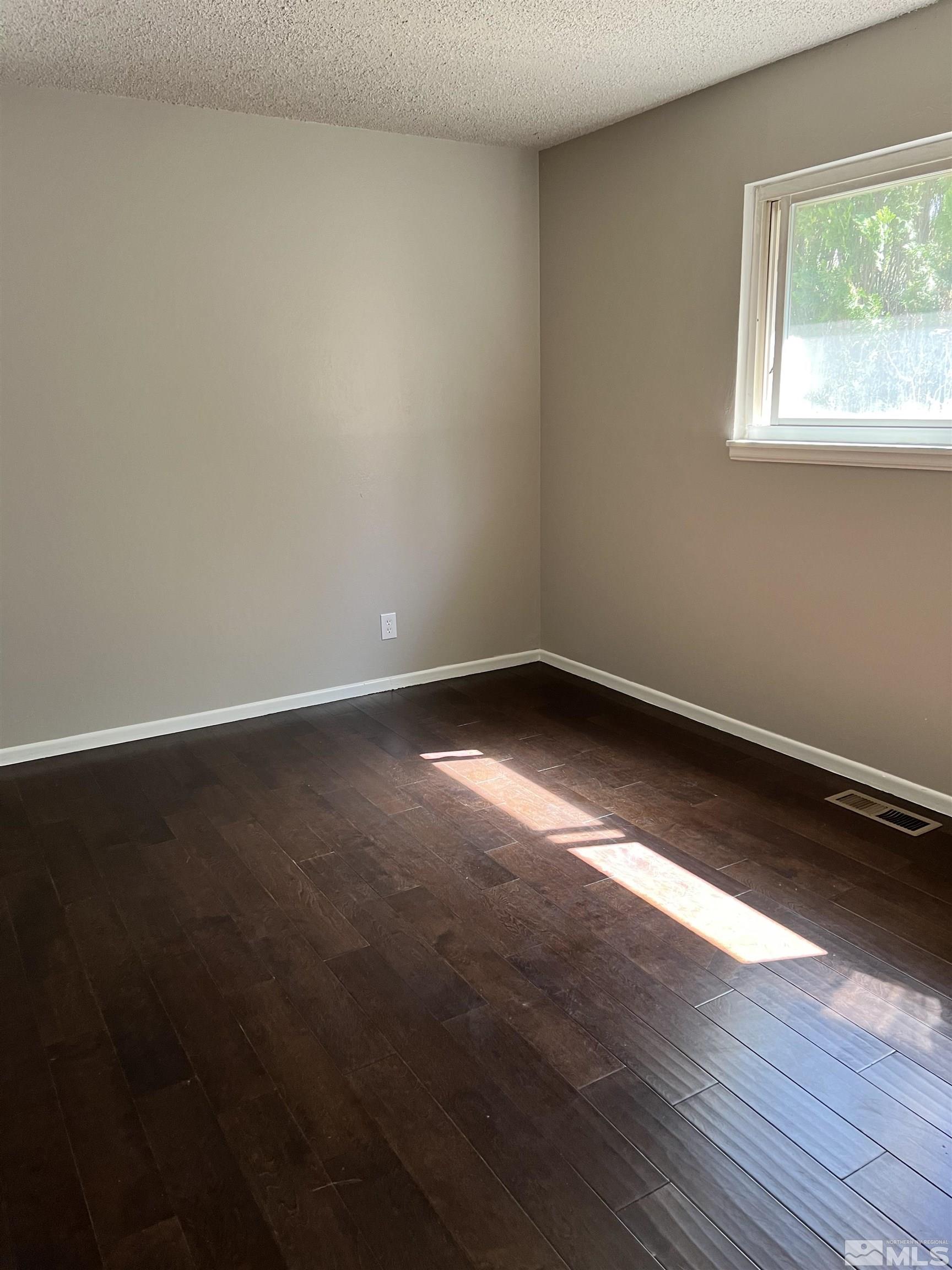 908 Lester Avenue Reno, NV 89502 - Photo 10 of 35 a view of an empty room with wooden floor and a window