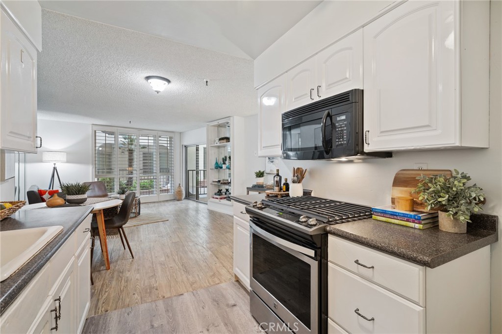 565 Esplanade, Unit 104 Redondo Beach, CA 90277 - Photo 17 of 42 a kitchen with granite countertop a stove a sink a refrigerator dining table and chairs