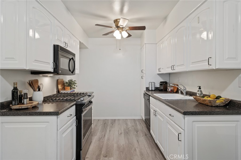 565 Esplanade, Unit 104 Redondo Beach, CA 90277 - Photo 20 of 42 a kitchen with stainless steel appliances granite countertop a sink stove and white cabinets with wooden floor