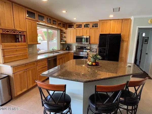 a kitchen with stainless steel appliances granite countertop a lot of cabinets a sink and a refrigerator
