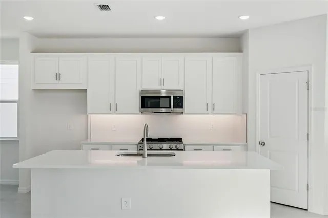 a kitchen with kitchen island a stove top oven and white cabinets