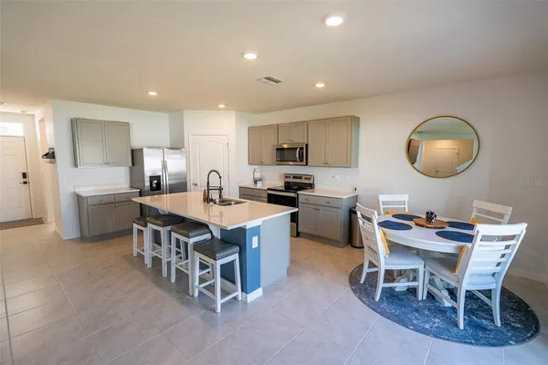 a kitchen with a dining table chairs and white appliances