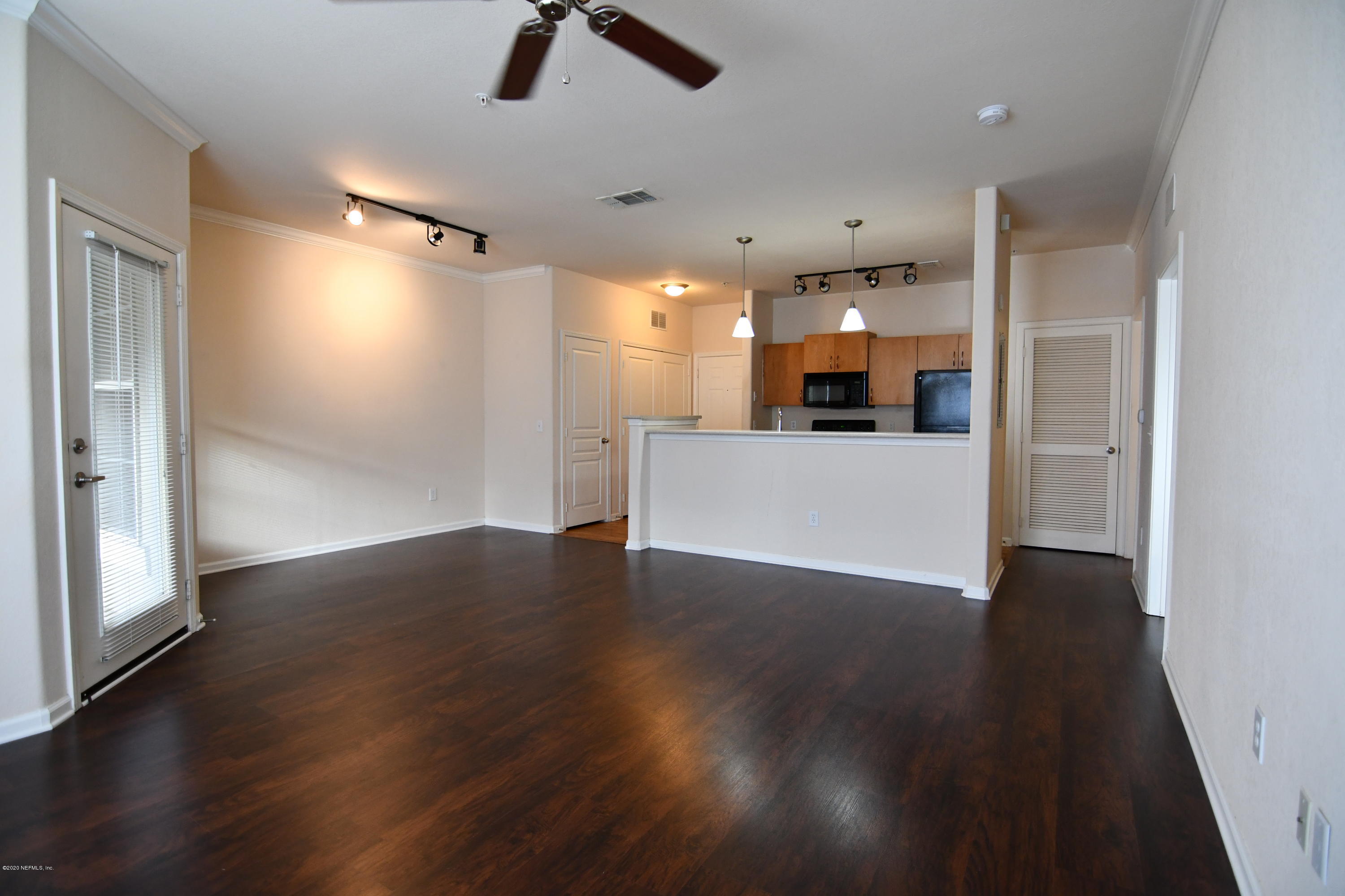 a view of a big room with wooden floor and windows