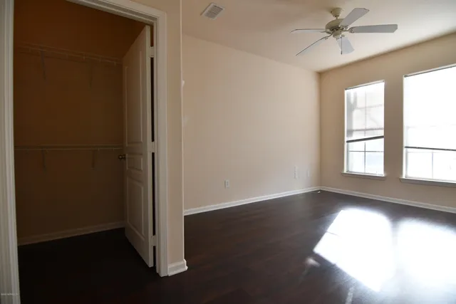 an empty room with wooden floor cabinet and windows