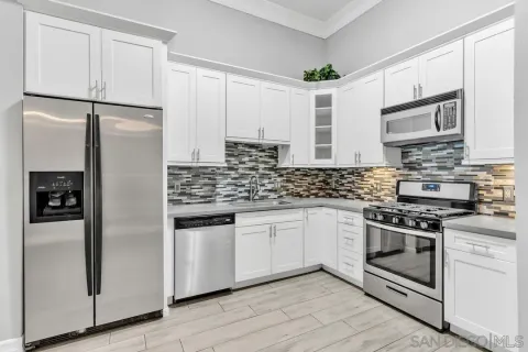 a kitchen with stainless steel appliances granite countertop a refrigerator a stove and a sink