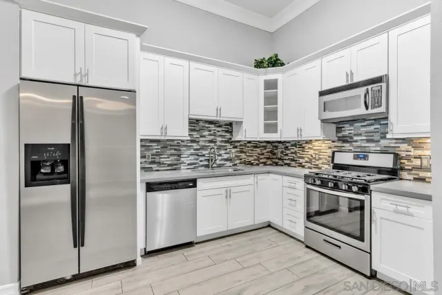 a kitchen with stainless steel appliances granite countertop a refrigerator a stove and a sink
