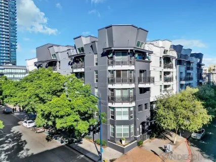 a front view of a multi story residential apartment building with yard and parking space