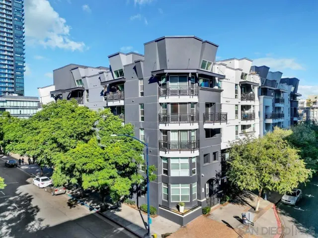 a front view of a multi story residential apartment building with yard and parking space
