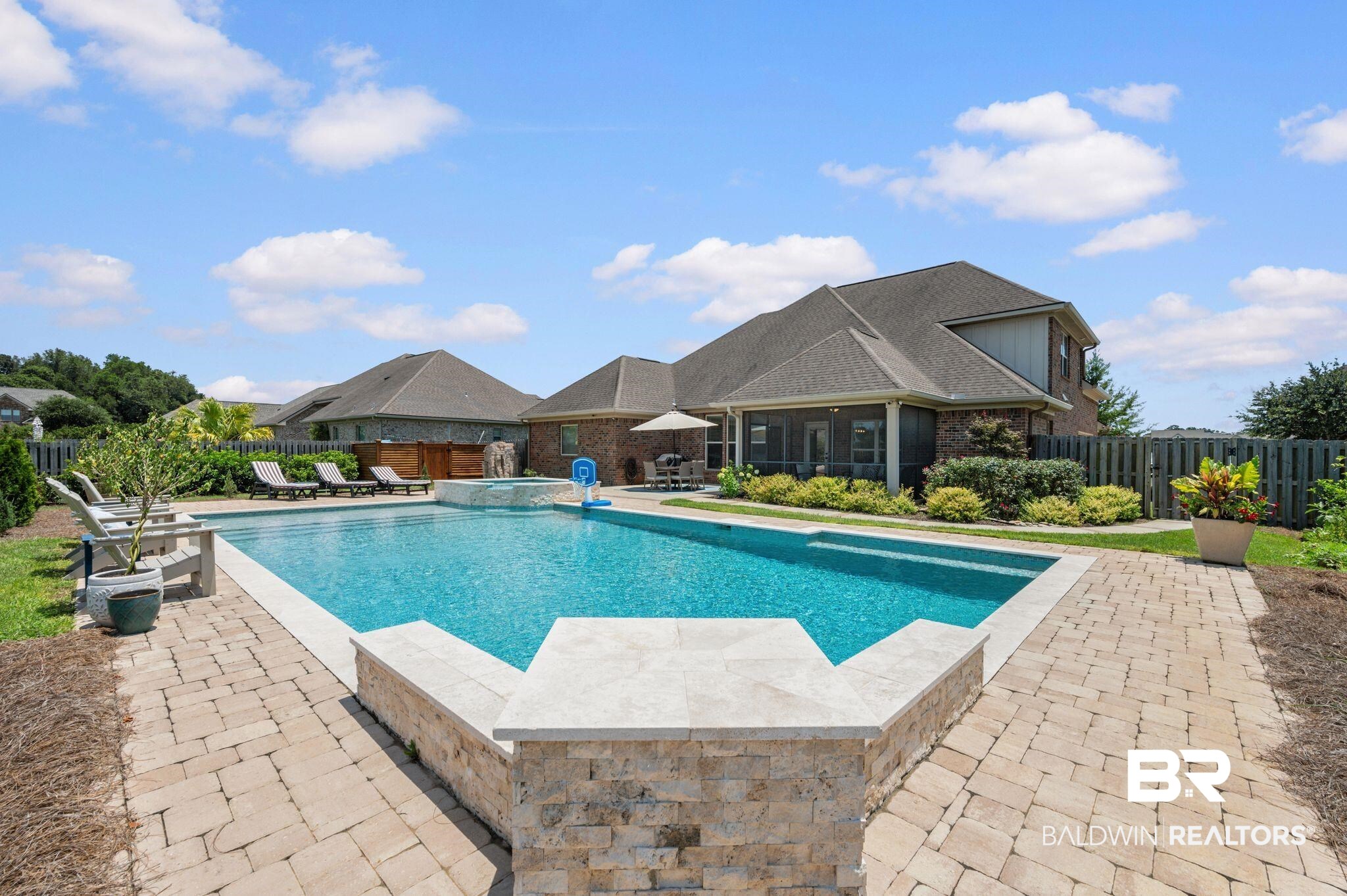 409 Fortune Drive Fairhope, AL 36532 - Photo 40 of 42 Geometric swimming pool with integrated spa, surrounded by stone paver decking and a privacy fence