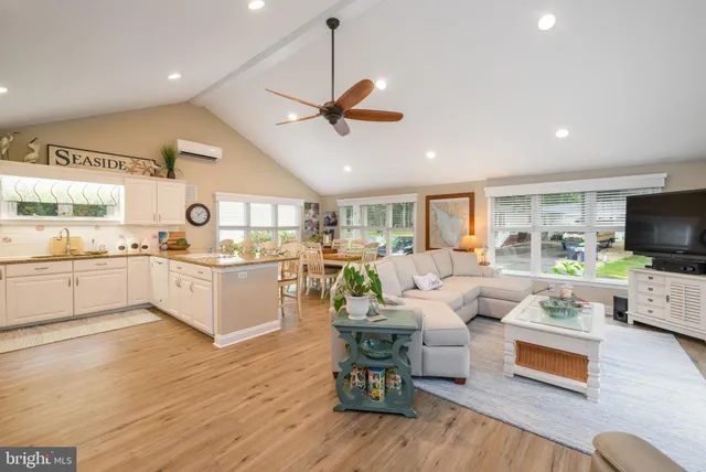 a living room with furniture kitchen view and a wooden floor