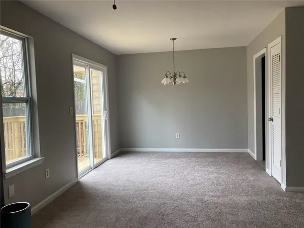 an empty room with chandelier fan and windows