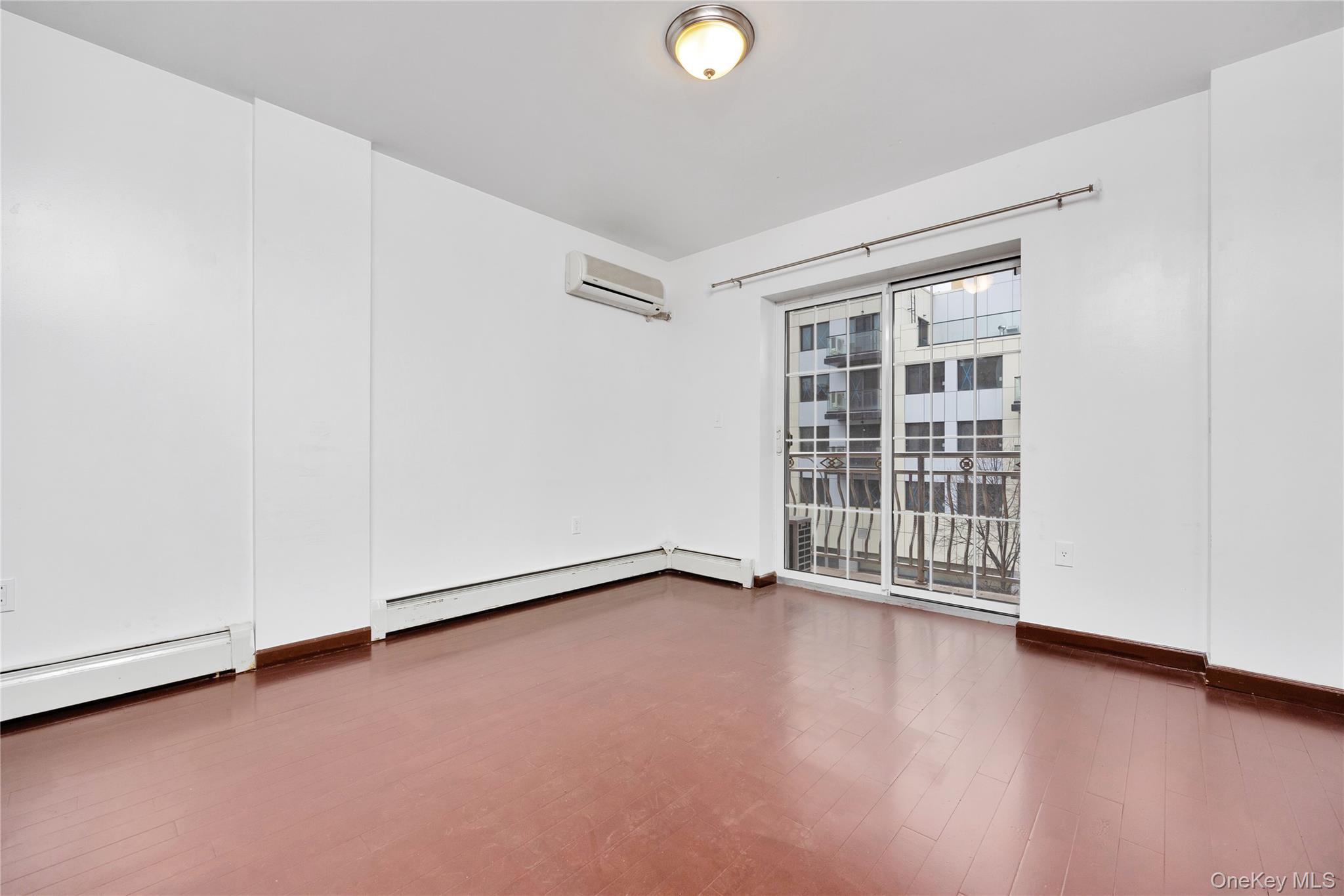 132-36 Pople Avenue, Unit 3A Queens, NY 11355 - Photo 16 of 24 Unfurnished room featuring baseboard heating, dark wood-type flooring, and a wall mounted air conditioner