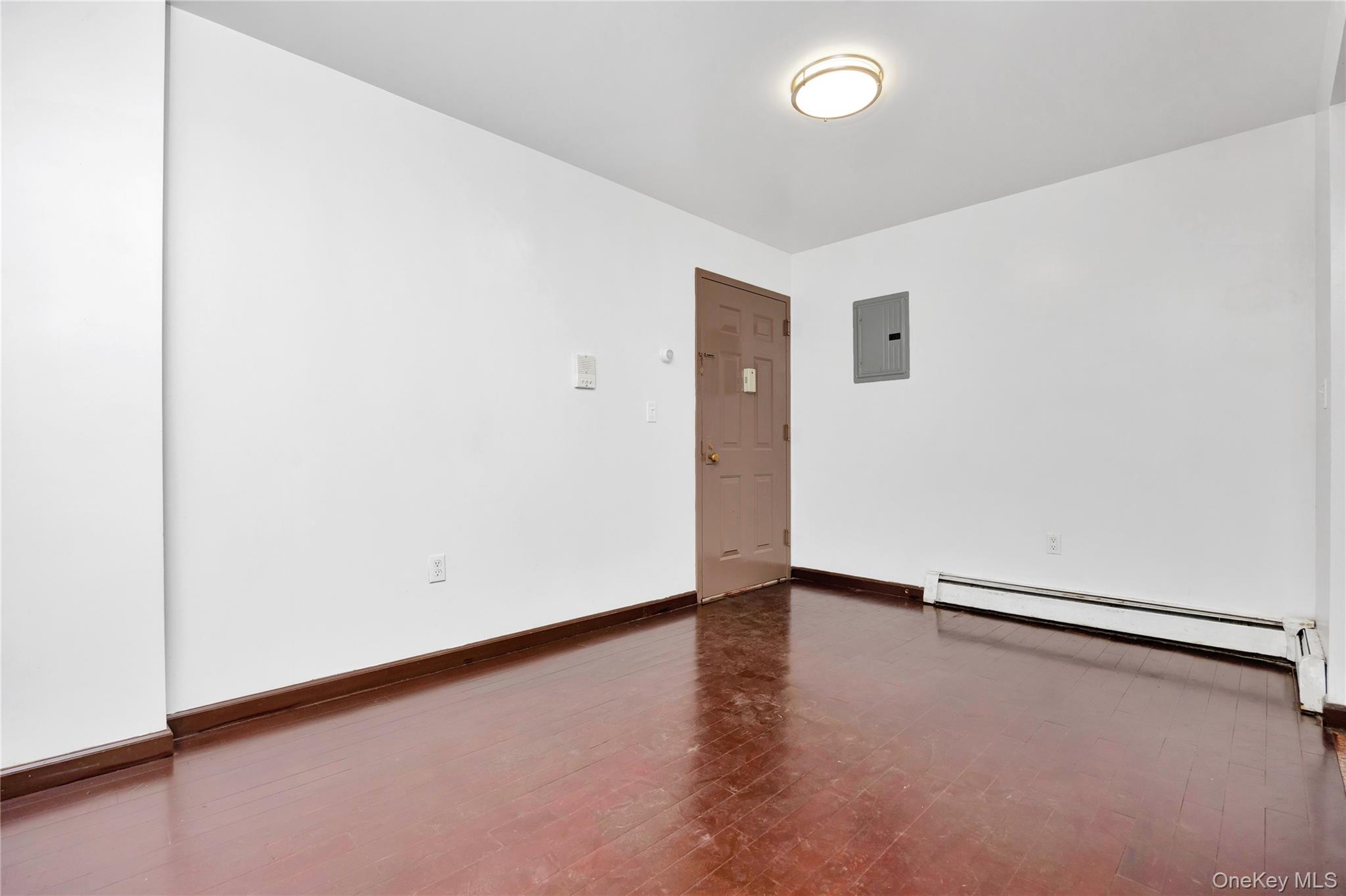 132-36 Pople Avenue, Unit 3A Queens, NY 11355 - Photo 9 of 24 Unfurnished room with baseboard heating, dark wood-style floors, and electric panel