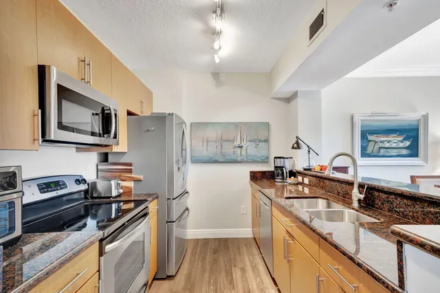 a kitchen with stainless steel appliances granite countertop a sink stove microwave and refrigerator