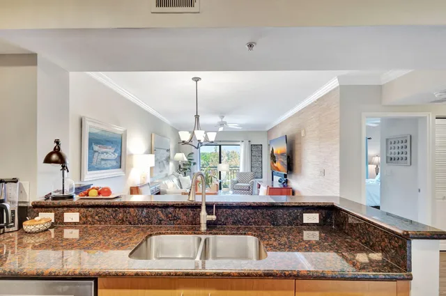 a view of a dining room and livingroom with furniture wooden floor a rug a painting and a chandelier