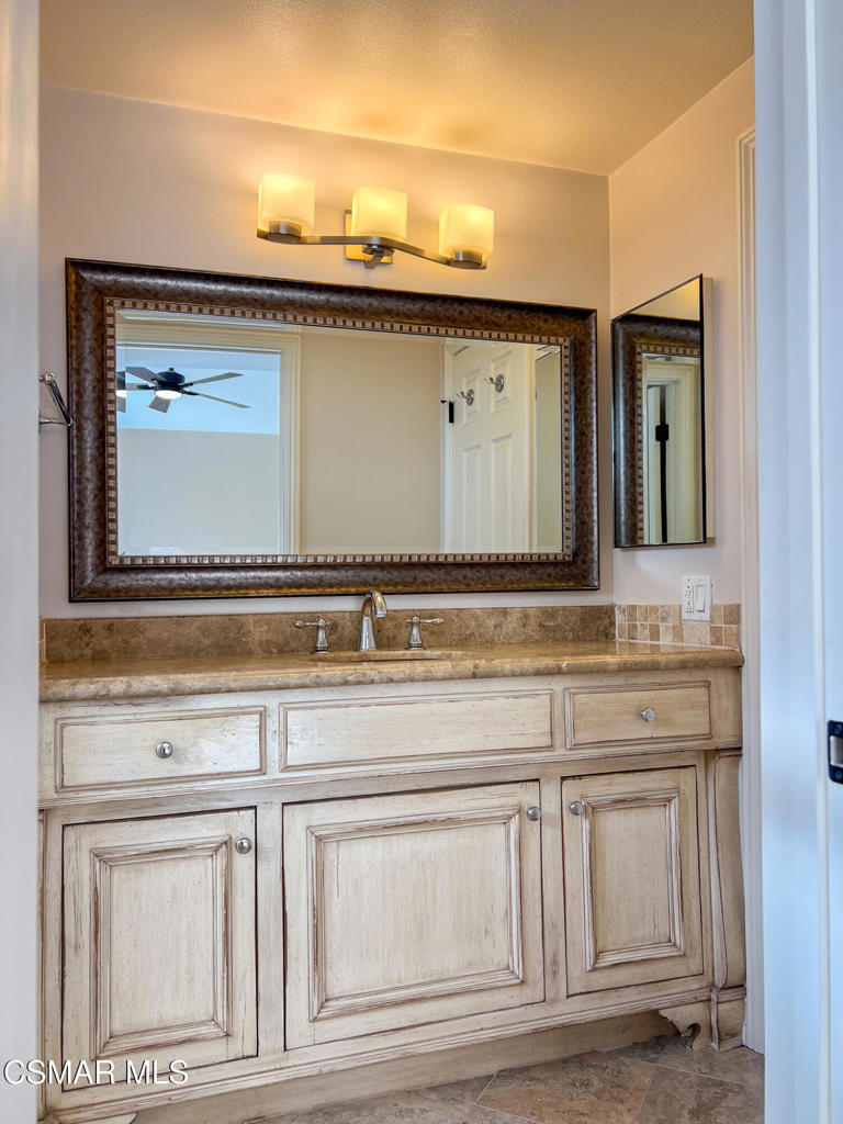 5458 Softwind Way Agoura Hills, CA 91301 - Photo 29 of 31 a bathroom with a sink a mirror and cabinets