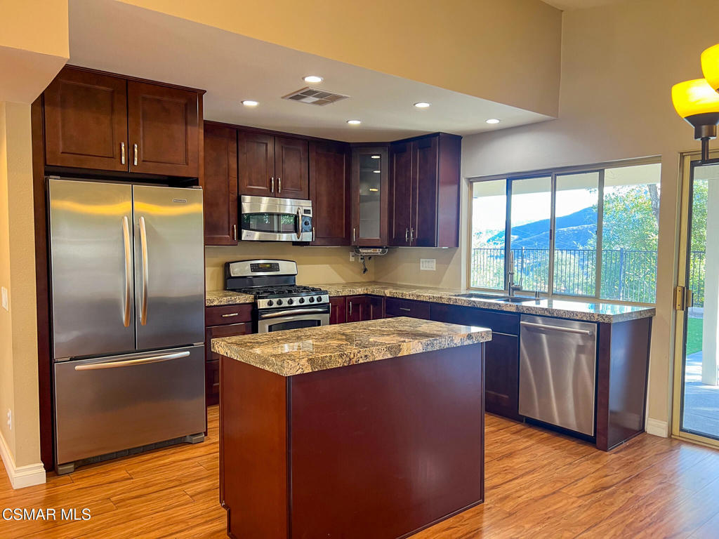 5458 Softwind Way Agoura Hills, CA 91301 - Photo 7 of 31 a kitchen with stainless steel appliances granite countertop a refrigerator a sink a stove a microwave and island