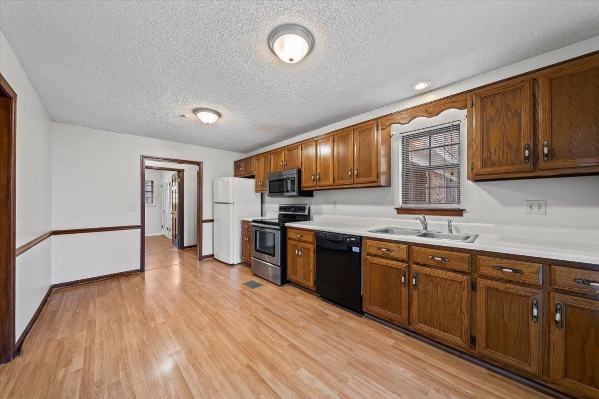 10060 Rosemark Road Atoka, TN 38004 - Photo 10 of 26 a kitchen with stainless steel appliances granite countertop wooden cabinets a refrigerator a sink a stove and wooden floors