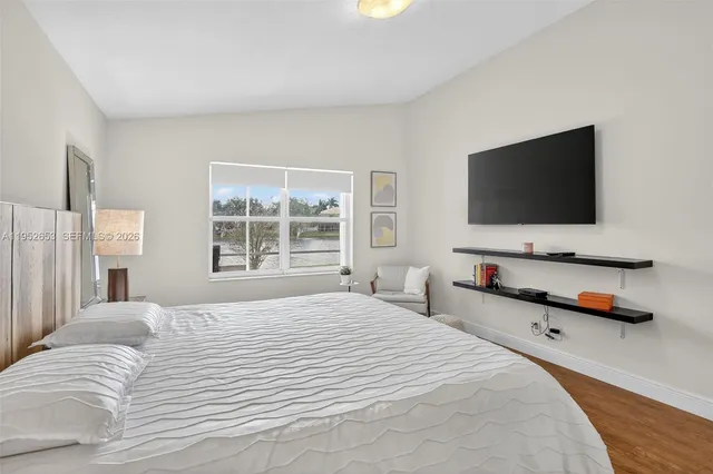 a bedroom with bed table and flat screen tv