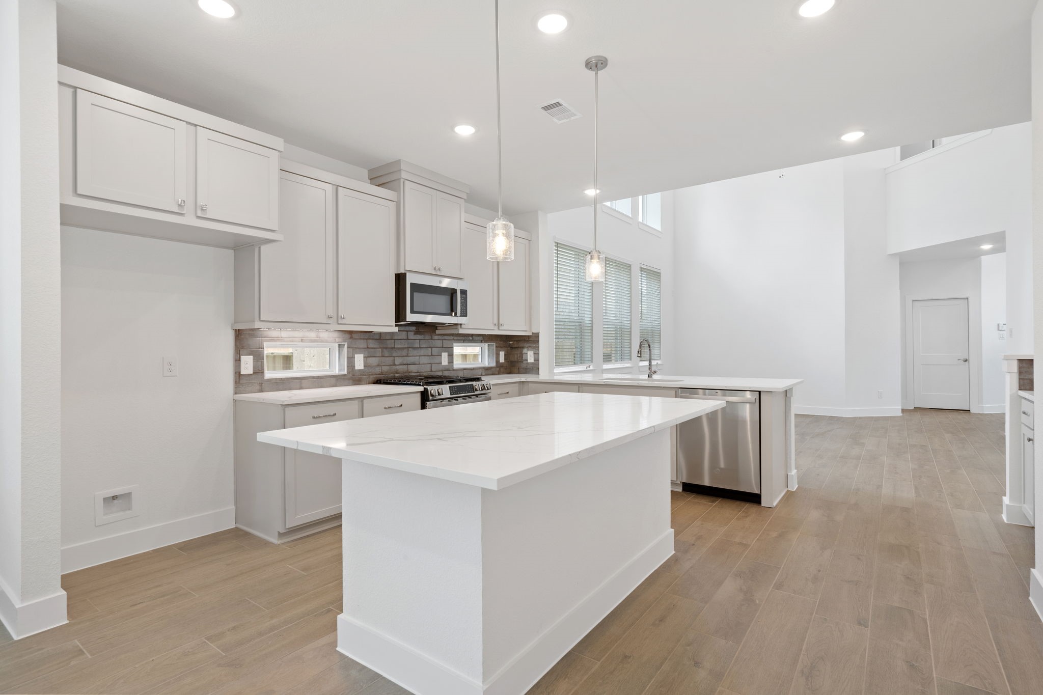 12846 Meadow Wind Way Conroe, TX 77302 - Photo 4 of 32 a large white kitchen with kitchen island a sink a center island stainless steel appliances and a cabinets