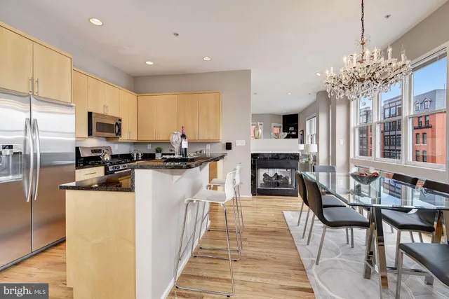 a kitchen with granite countertop a refrigerator a stove a sink a dining table and chairs with wooden floor