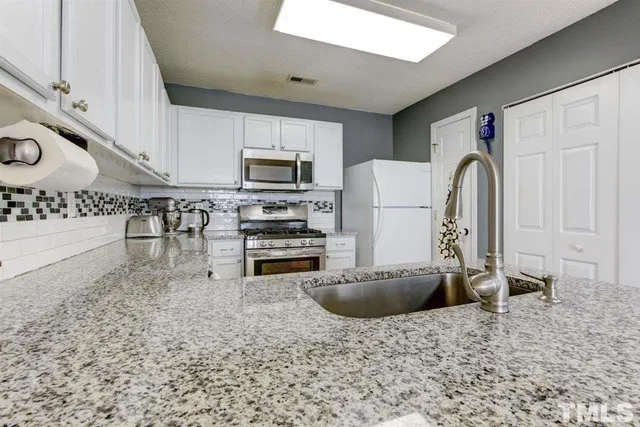 a kitchen with granite countertop a stove top oven a sink dishwasher and a refrigerator with wooden floor