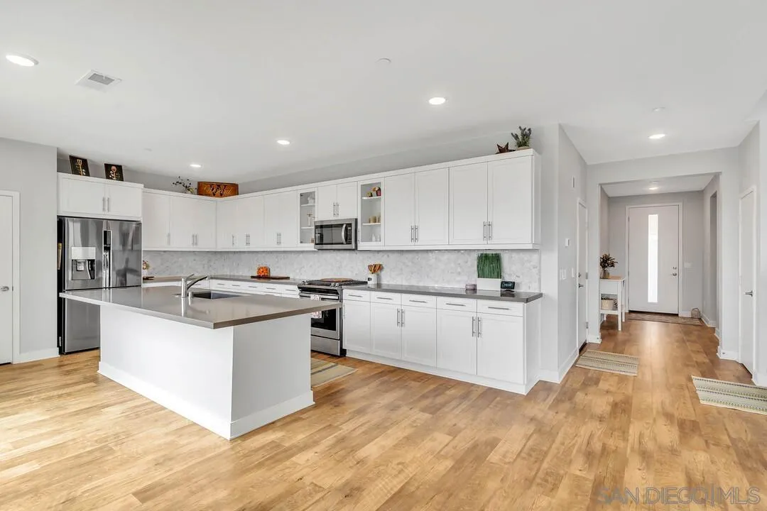 8869 Trailridge Avenue Santee, CA 92071 - Photo 8 of 48 a kitchen with stainless steel appliances granite countertop a stove top oven a sink a refrigerator and white cabinets