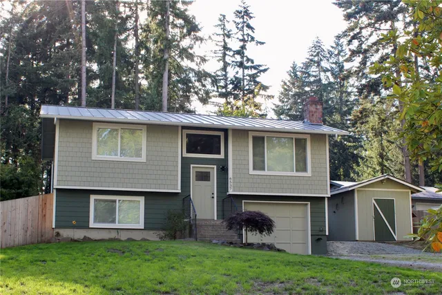 a view of a yard in front of a house with plants and large tree