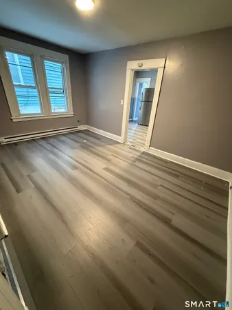 a view of an empty room with wooden floor and a window