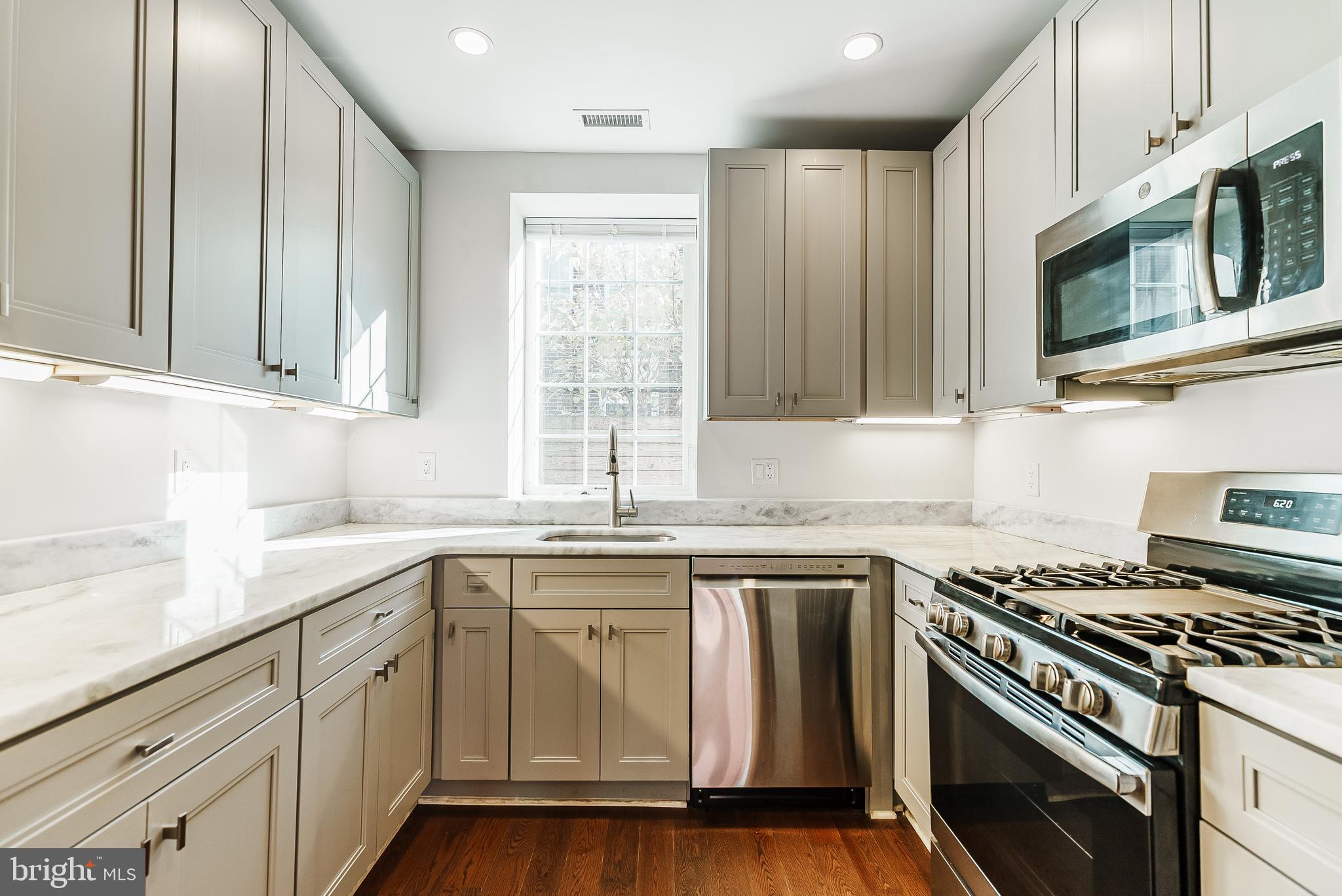 1331 South Dover Street Philadelphia, PA 19146 - Photo 9 of 24 a kitchen with stainless steel appliances white cabinets granite counter tops and a window