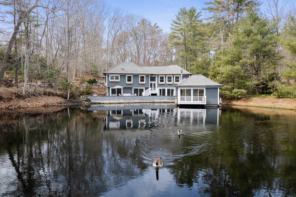 a view of a house next to a lake with large trees