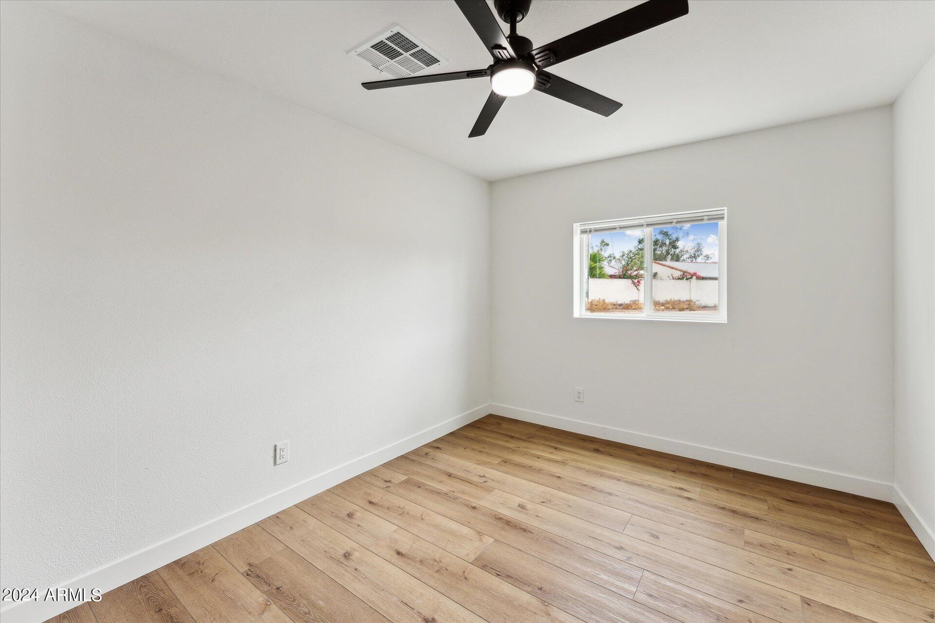 1548 North Upland Circle, Unit C Mesa, AZ 85201 - Photo 14 of 21 an empty room with wooden floor and windows