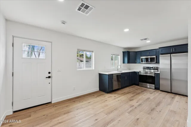 a large kitchen with a wooden floor and stainless steel appliances