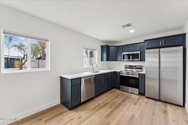 a large kitchen with stainless steel appliances granite countertop a stove a sink dishwasher a refrigerator and a wooden floor