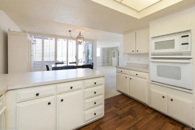 a kitchen with cabinets stainless steel appliances a sink and wooden floor