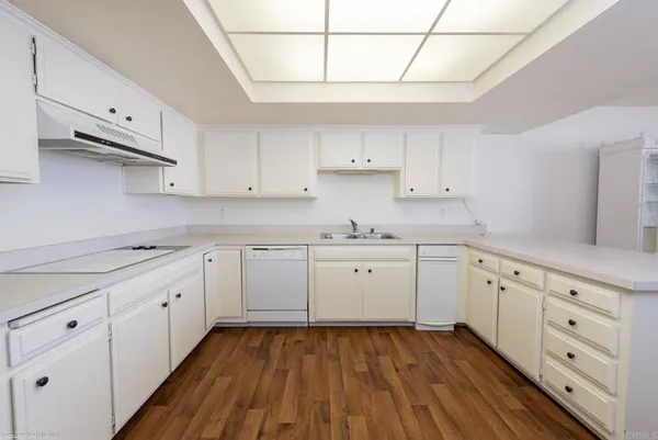 a kitchen with cabinets stainless steel appliances a sink and wooden floor