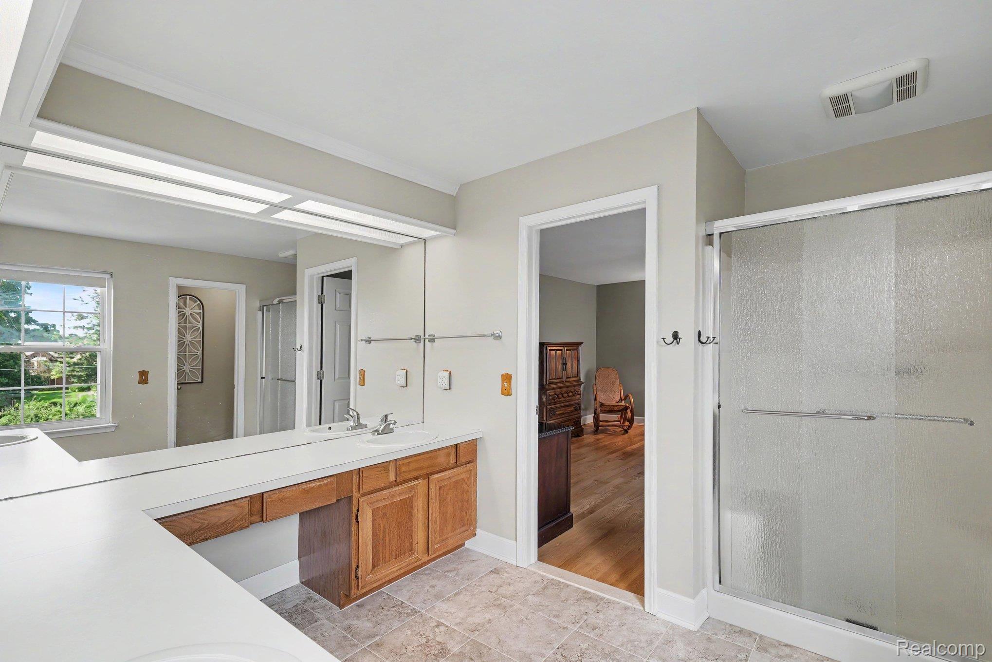 1692 Ridgecrest Rochester, MI 48306 - Photo 18 of 31 Double vanity with white countertop, wood cabinetry, and a full-width mirror