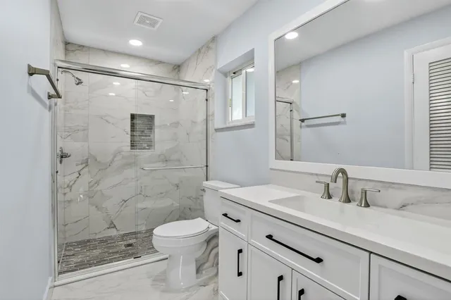 a bathroom with a sink toilet a mirror and shower