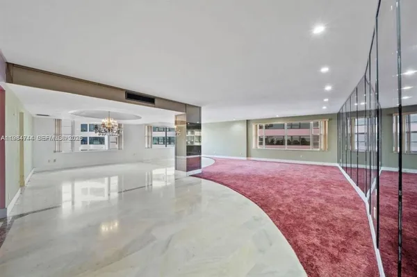 an empty room with a fireplace and chandelier