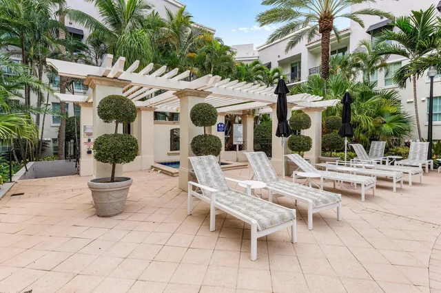 a view of a patio with a dining table and chairs potted plants and palm trees