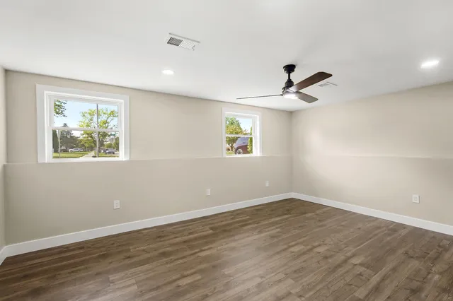 a view of empty room with wooden floor and fan