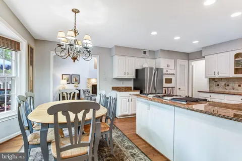 a kitchen with stainless steel appliances granite countertop a dining table chairs and a refrigerator