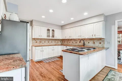 a kitchen with stainless steel appliances granite countertop a stove a sink and white cabinets