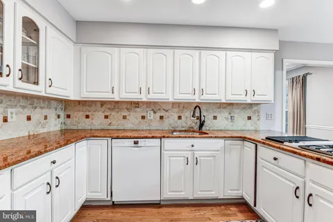 a kitchen with granite countertop white cabinets and sink