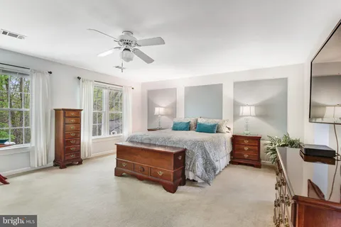 a spacious bedroom with a bed and glass walk in closet