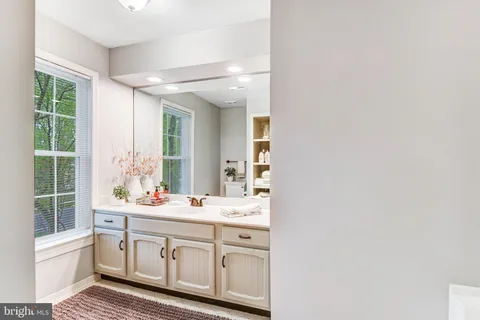 a bathroom with a sink a mirror and next to a window