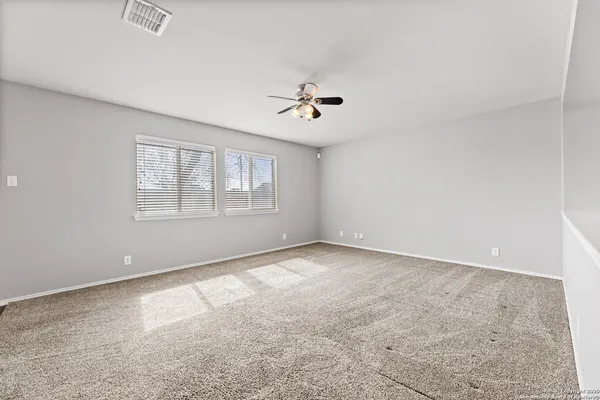 an empty room with windows and ceiling fan