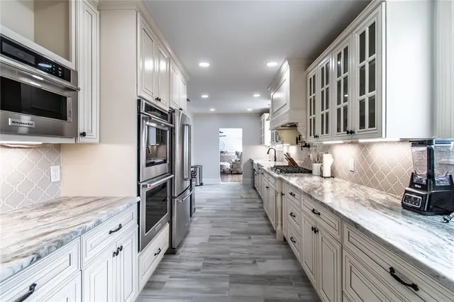a large kitchen with stainless steel appliances granite countertop a lot of counter space and wooden floor