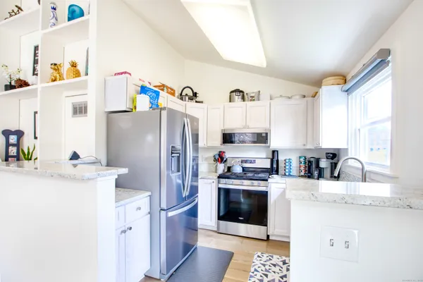 a kitchen with stainless steel appliances granite countertop a refrigerator a stove a sink and a refrigerator with wooden floor